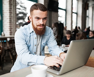 man working with laptop and papers while sitting at tabl
